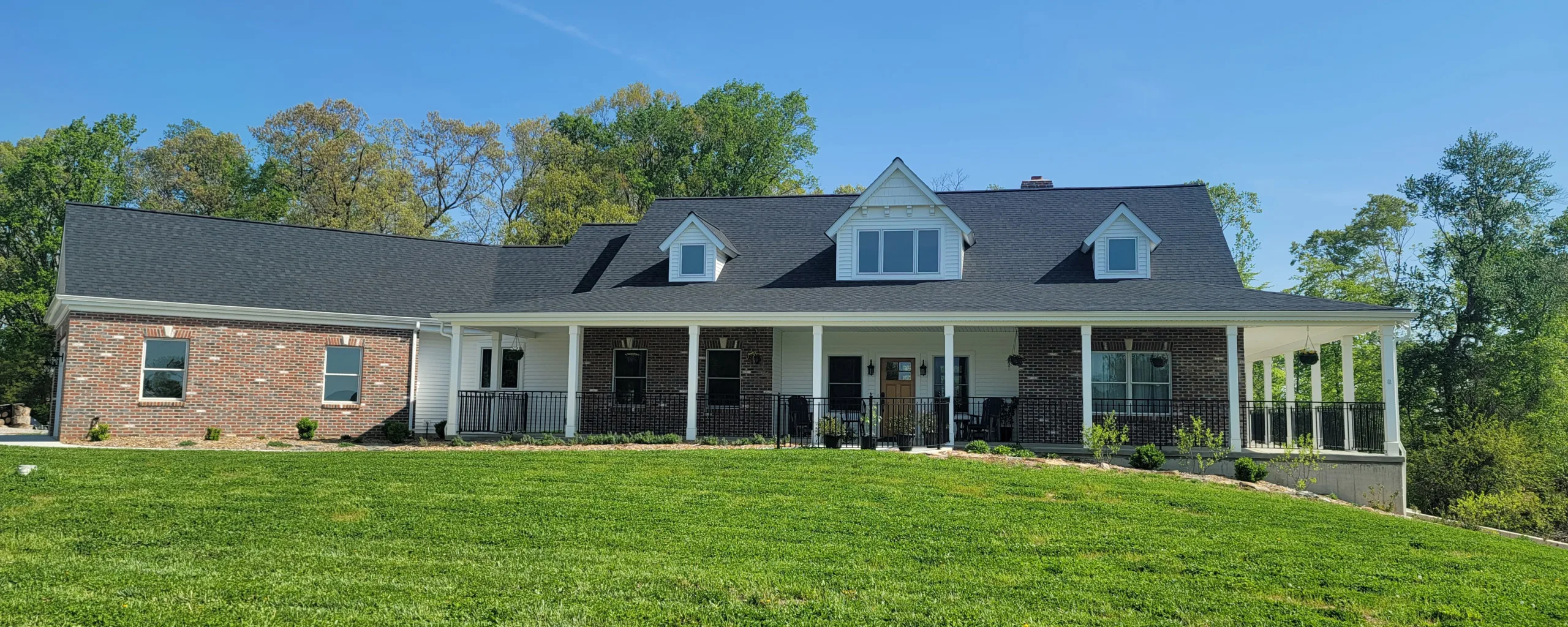 A brick home with a green lawn and trees.